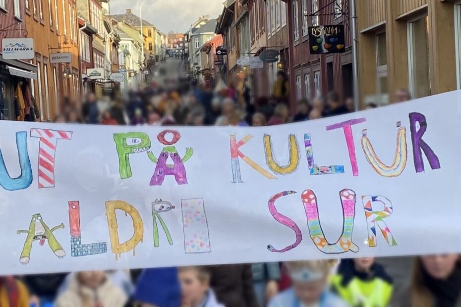 masse mennesker i Kjerkgata på Røros utkledd med vintertema, og en banner med teksten "Ut på kultur aldri sur"