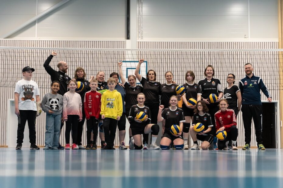en gruppe mennesker i treningsklær som holder flere volleyballer i en idrettshall